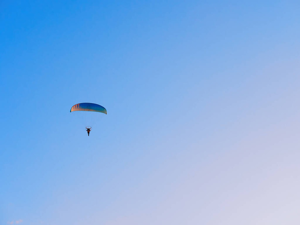 Paraglider flies on a paraglider over the city on a warm evening - Фото, изображение