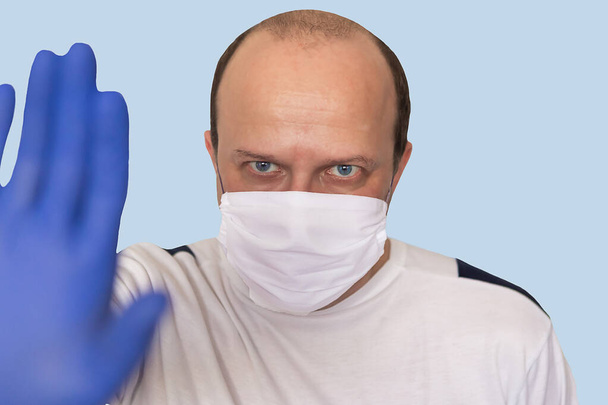 医療用マスクの男は、カメラへの停止ジェスチャーを示しています。コロナウイルスの概念 - 写真・画像