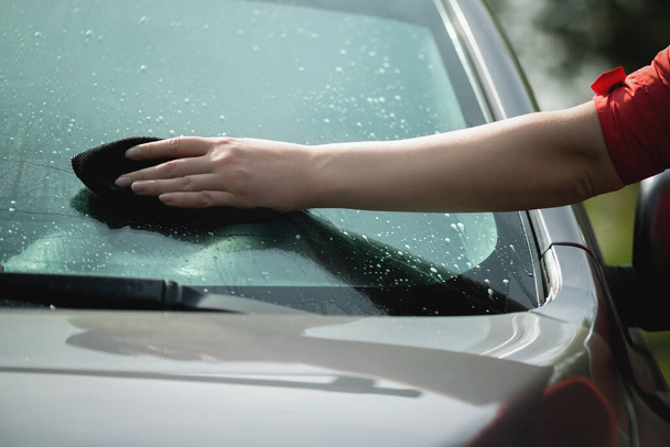 Cleaner is cleaning a car window glass with a rag and detergent close up. - Foto, Imagen