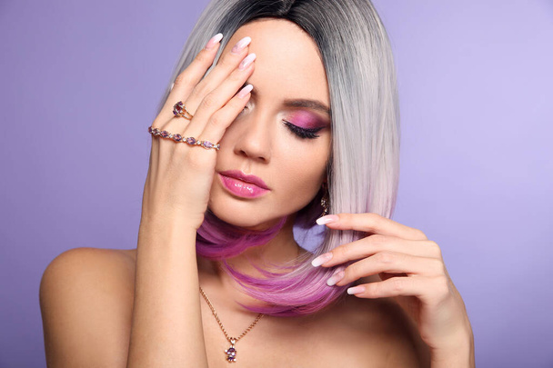 Beautiful lady presents amethyst ring and bracelet jewelry set. Woman portrait with ombre bob short hairstyle and manicured nails. Beauty makeup. Gorgeous model isolated on purple background. - Photo, Image