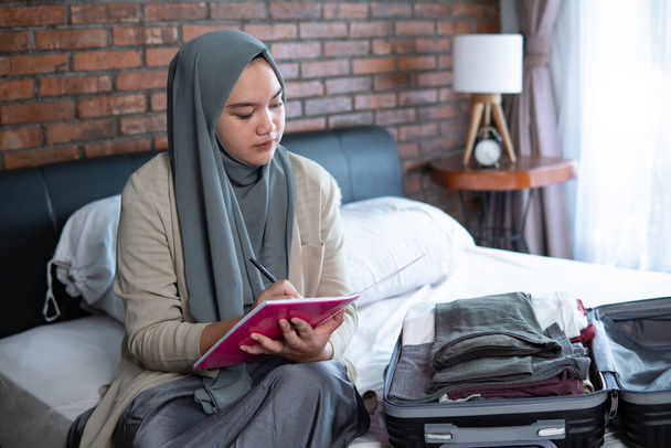 muslim asian woman checking list of luggage - Foto, imagen