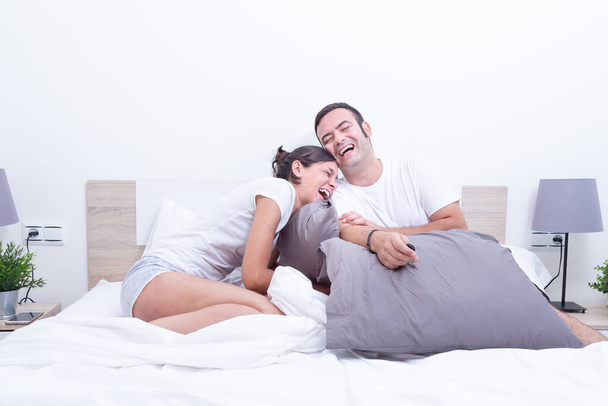 Feliz risa relajado joven pareja en la cama en casa. felicidad en concepto de relación
. - Foto, imagen