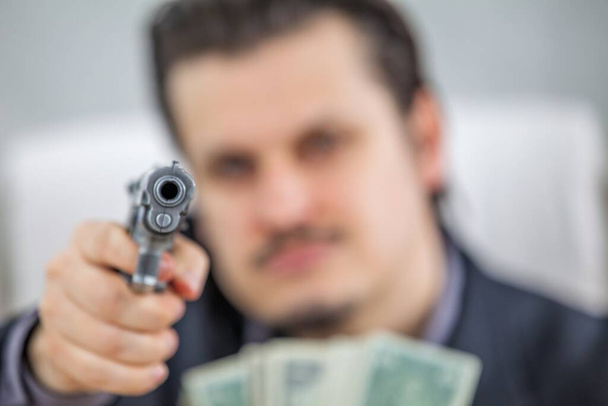 A businessman is pointing a gun at someone. - Φωτογραφία, εικόνα