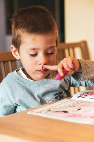 POZNAN, PUOLA huhtikuu 13, 2020: Pieni kaksivuotias poika istuu pöydän ääressä ja värittää Thomas and Friends kirjaa
. - Valokuva, kuva
