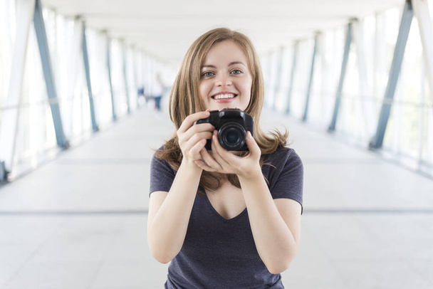 Joven mujer caucásica fotógrafa sosteniendo una cámara digital en las manos, tomando una foto o video
 - Foto, imagen