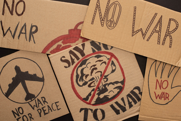 vista superior de carteles de cartón sin letras de guerra y dibujos sobre fondo negro
 - Foto, Imagen