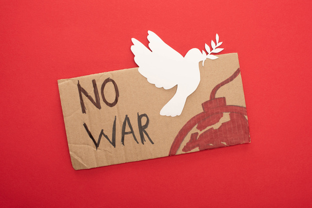 vista superior del cartel de cartón sin letras de guerra y bomba con paloma de papel blanco sobre fondo rojo
 - Foto, Imagen