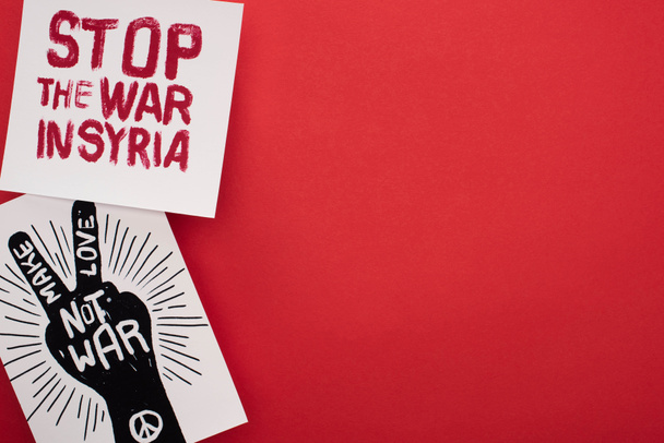 top view of drawings with make love not war and stop war in Syria lettering on red background - Foto, Imagem
