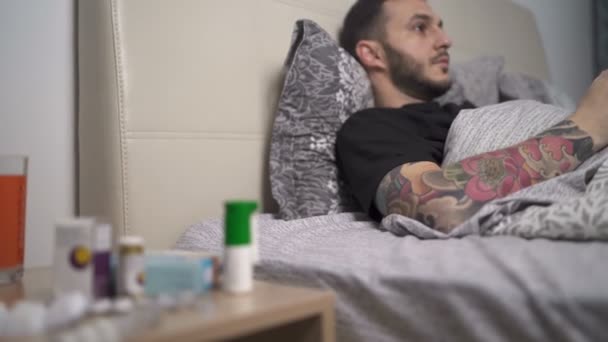 Mężczyzna w domowej kwarantannie gra w gry wideo leżące w łóżku - Materiał filmowy, wideo