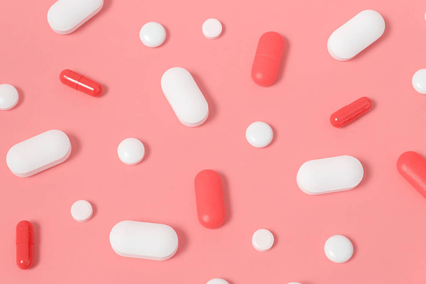 White and pink pills on fun bright pink background. Big and small vitamins for skin. Beauty Care Supplements and Products. Healthcare concept. Top view. - 写真・画像