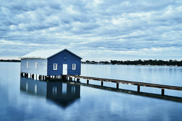 Maalaismainen sininen talo, jossa puinen silta keskellä vettä
 - Valokuva, kuva