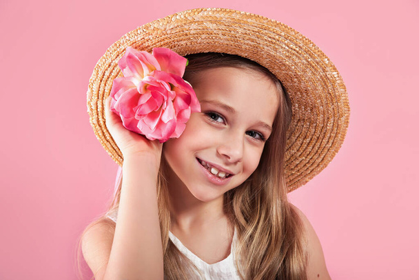 Καλοκαιρινό portait ενός μικρού κοριτσιού με ψάθινο καπέλο σε ροζ φόντο στούντιο - Φωτογραφία, εικόνα