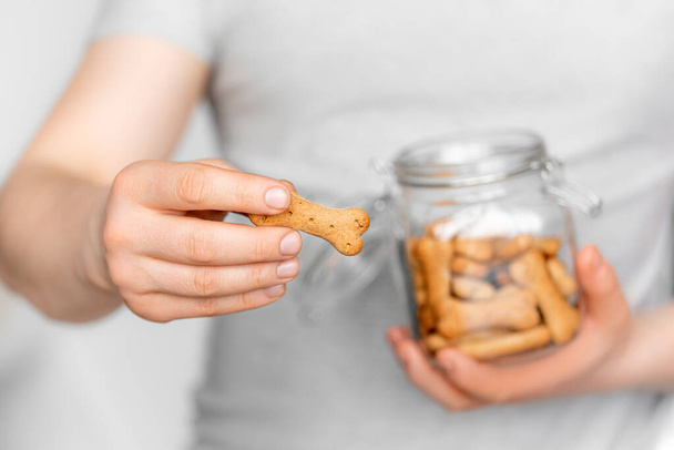 man holds dog cookies in the jar on a light background - Photo, Image