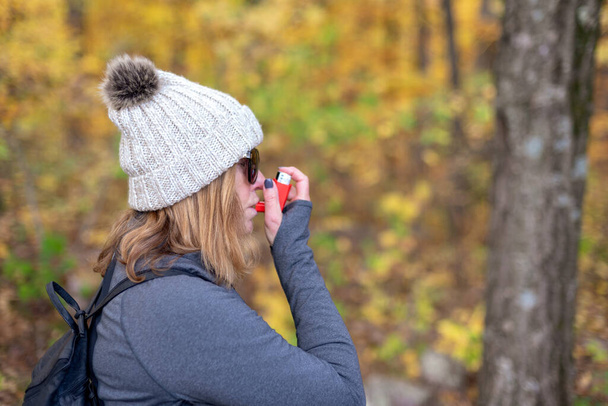 woman using prescription inhaler while hiking outdoors in cold weather and high elevation - Photo, Image