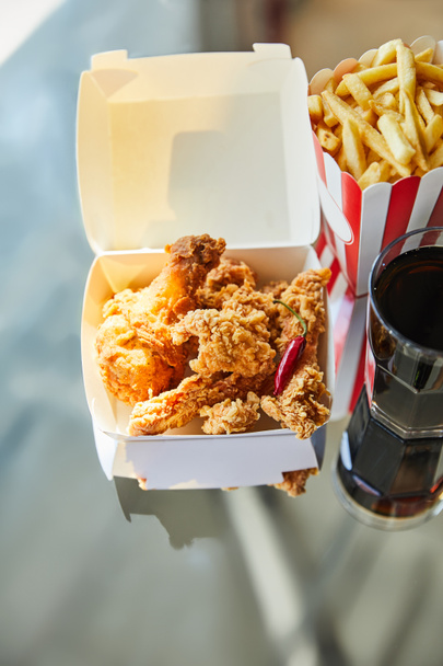 deep fried chicken, french fries and soda in glass on glass table in sunlight - Photo, Image