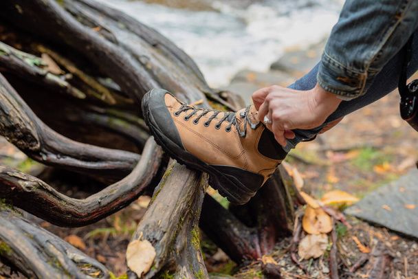 woman tying hiking boot outdoors on trail in fall - Photo, Image
