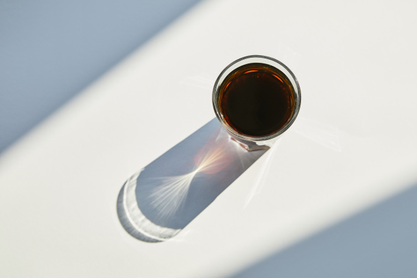 top view of tasty soda in glass on white table in sunlight with shadow - Фото, зображення