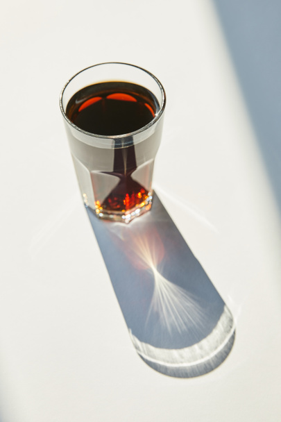tasty soda in glass on white table in sunlight with shadow - Photo, Image
