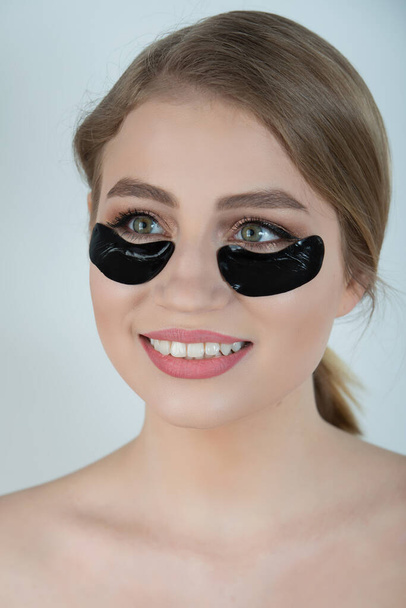 Under Eye Skin Black Patch. Closeup Of Beautiful Young Woman Face With Moisturizing Collagen Mask Pad On Healthy Fresh Facial Skin On White Background. High Resolution. - Foto, immagini