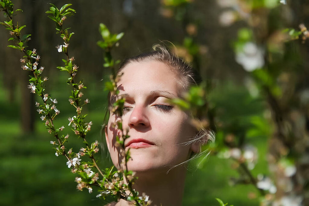 Retrato de una joven rubia caucásica con olor a ojo cerrado en la avenida del árbol de primavera con hierba
 - Foto, Imagen