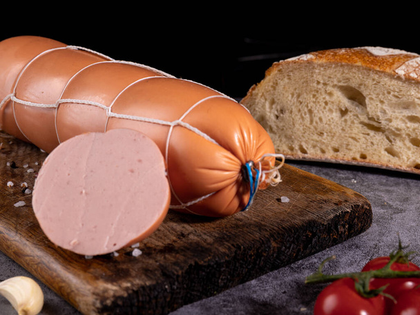 boiled sausage on a wooden board on a dark background - Photo, Image