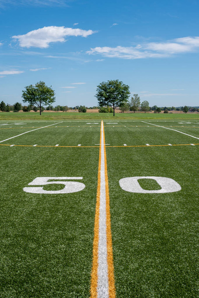 50-ярдовая линия на пустом футбольном поле под ясным голубым небом
 - Фото, изображение