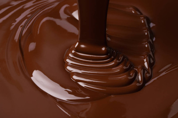 Warme chocolademelk. stromende zoete siroop, donkere chocolade achtergrond - Foto, afbeelding