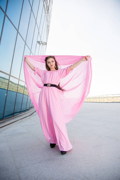beautiful  young woman in pink dress posing on terrace  - Фото, изображение