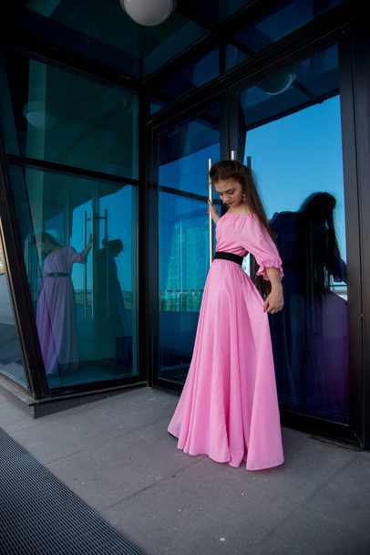 beautiful  young woman in pink dress posing on terrace  - Фото, изображение