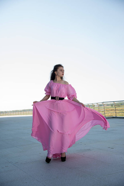 beautiful  young woman in pink dress posing on terrace  - Photo, Image