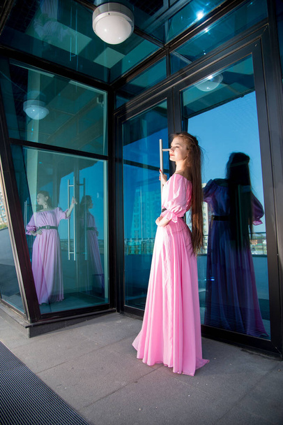 beautiful  young woman in pink dress posing on terrace  - 写真・画像