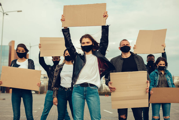 Μια ομάδα ανθρώπων με μάσκα που βγήκαν με αφίσες για να διαμαρτυρηθούν Η διαμαρτυρία του πληθυσμού ενάντια στον κορωναϊό και ενάντια στην εισαγωγή της συνάντησης καραντίνας για τον κορωναϊό και τα ανθρώπινα δικαιώματα. Αντιγραφικός χώρος - Φωτογραφία, εικόνα