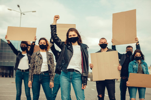 抗議するためにポスターで出てきたマスクを持つ人々のグループコロナウイルスに対する集団の抗議とコロナウイルスと人々の権利に関する検疫会議の導入に対して。コピースペース - 写真・画像