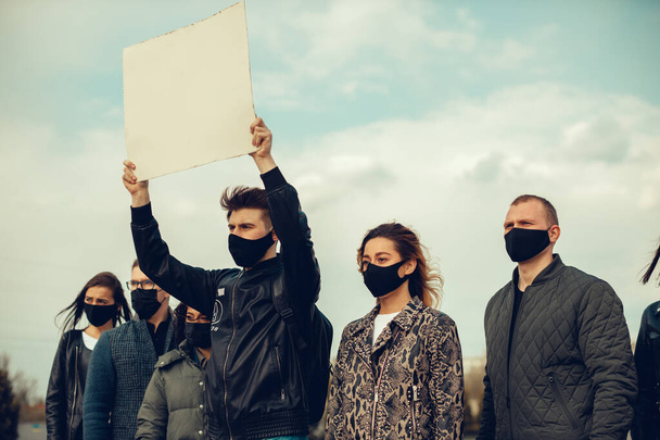 Группа людей в масках, которые вышли с плакатами в знак протеста Протест населения против коронавируса и против введения карантинного совещания о коронавирусе и правах людей. Copyspace
 - Фото, изображение