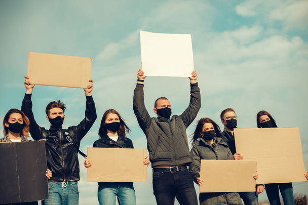 Ryhmä naamioituneita ihmisiä, jotka esittivät julisteita protestoidakseen väestön mielenosoitusta koronavirusta vastaan ja karanteenikokouksen järjestämistä vastaan koronaviruksesta ja ihmisten oikeuksista. Kopioi
 - Valokuva, kuva