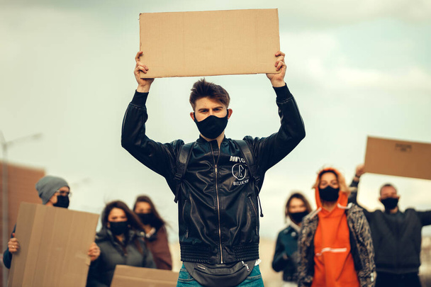 Группа людей в масках, которые вышли с плакатами в знак протеста Протест населения против коронавируса и против введения карантинного совещания о коронавирусе и правах людей. Copyspace
 - Фото, изображение