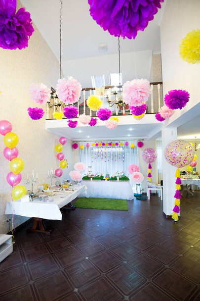 Una gran habitación con techos altos decorada con globos grandes y pompones de papel para el cumpleaños del niño. Interior de la habitación bellamente decorado
 - Foto, imagen