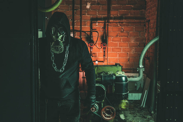 Homem com máscara de gás e um martelo na sala das máquinas. Conceito de perigo nuclear, biológico e químico
. - Foto, Imagem