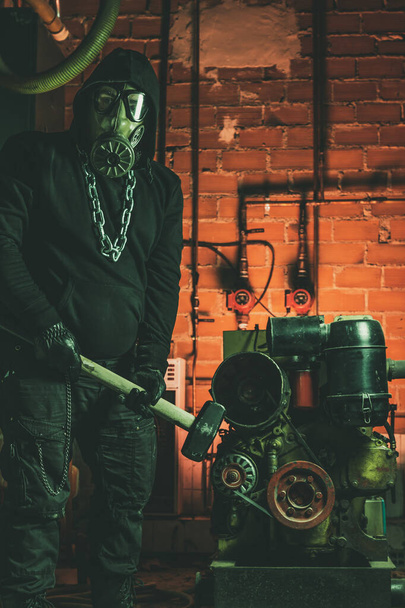 Homme avec masque à gaz et un marteau dans la salle des machines. Concept de danger nucléaire, biologique et chimique
. - Photo, image