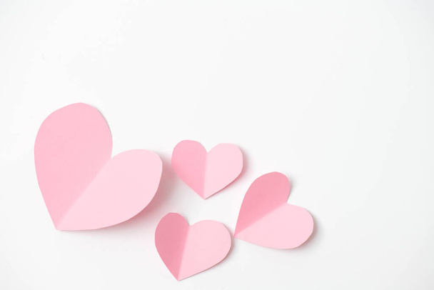 Paper elements in shape of heart flying on white paper background. Love and Valentine's day concept. Birthday greeting card design. - Fotó, kép