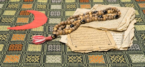 Мусульманські молитовні намистини зі стародавніми сторінками з Корану. Ісламська та мусульманська концепції. Стародавні аркуші паперу з арабської книги. - Фото, зображення