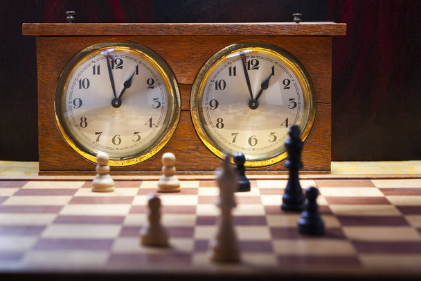 Antiguo reloj de ajedrez vintage de madera con un final en el tablero de ajedrez
  - Foto, Imagen