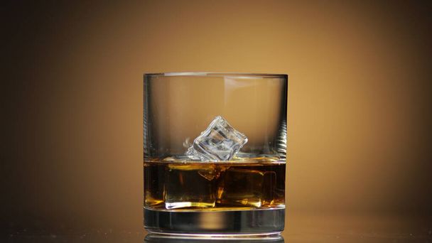 Алкоголь пьет виски, коньяк в стакан со льдом. Темный фон
. - Фото, изображение