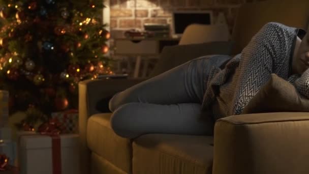 Woman sleeping on the sofa and colorful Christmas tree - Filmagem, Vídeo