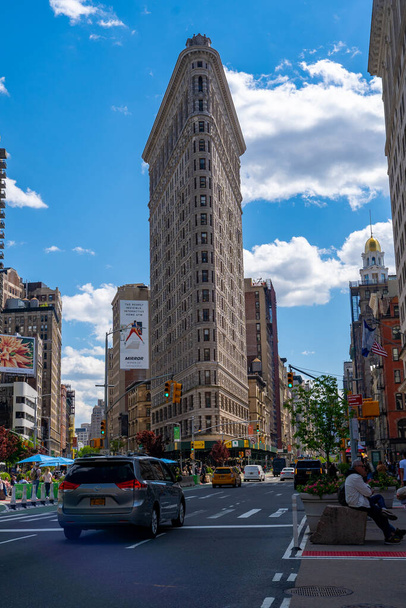 Nova York, EUA - MAIO 10, 2019: Fachada de construção de ferro plano, um dos primeiros arranha-céus já construídos, com a NYC Fifth Avenue e as pessoas ao seu redor
. - Foto, Imagem