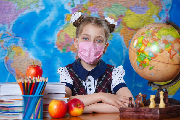 The schoolgirl at her Desk in a medical mask - Foto, immagini