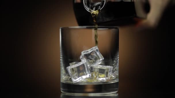 Pouring whiskey, cognac into glass. Dark background. Pour of alcohol drink - 映像、動画