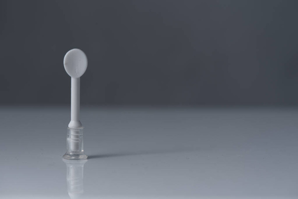 Тягач или присоска для контактных линз, стоит на белом столе и сером фоне
 - Фото, изображение