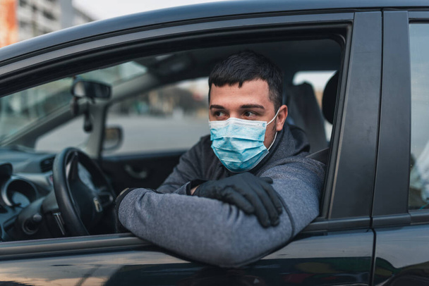 Mann mit medizinischer Maske und Gummihandschuhen zum Schutz vor Bakterien und Viren während der Autofahrt. Maskierter Mann in einem Auto. Coronavirus, Krankheit, Infektion, Quarantäne, Covid-19 - Foto, Bild