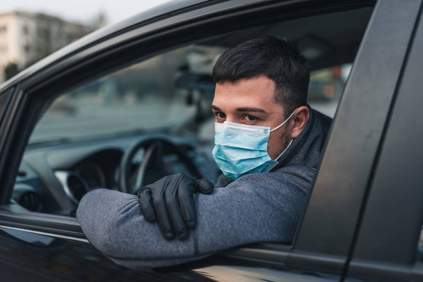 Людина в медичній масці та гумових рукавичках захищає себе від бактерій та вірусів під час водіння автомобіля. замаскований чоловік у машині. коронавірус, хвороба, інфекція, карантин, коїд-19
 - Фото, зображення